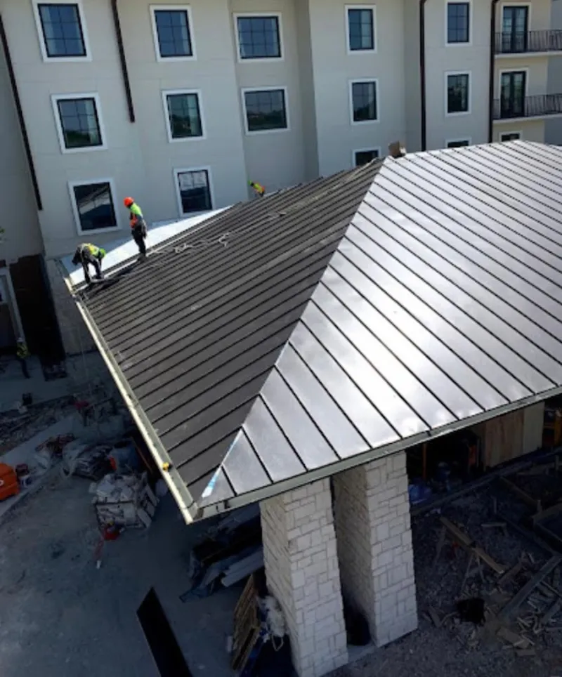 Crew installing standing seam metal roof panels on a commercial project in Binghamton